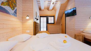 Um quarto de cabana de madeira aconchegante, com uma cama, uma janela e uma televisão na parede.