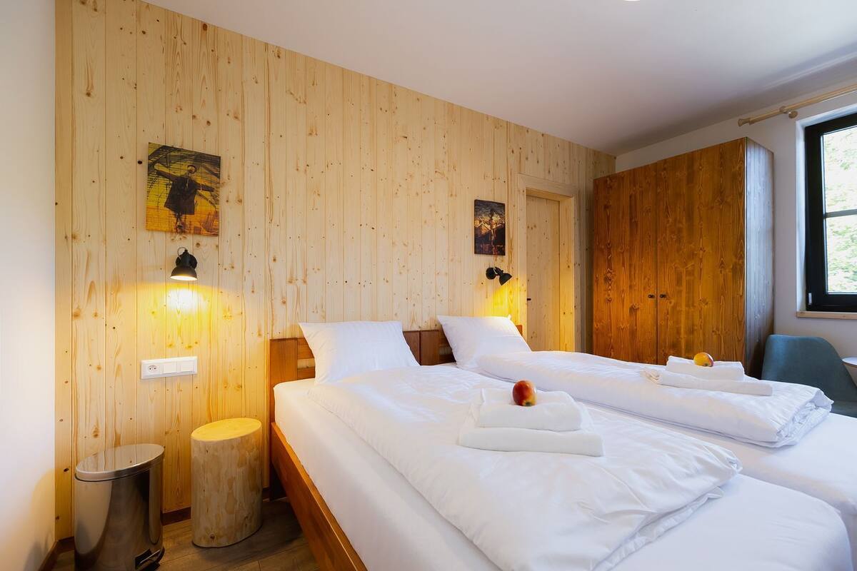 Ein Hotelzimmer mit zwei Betten, Holzwandverkleidung, Kunstwerken und einem Fenster.