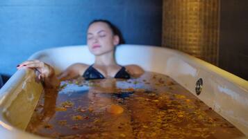 A person in a bathtub filled with water and rose petals.