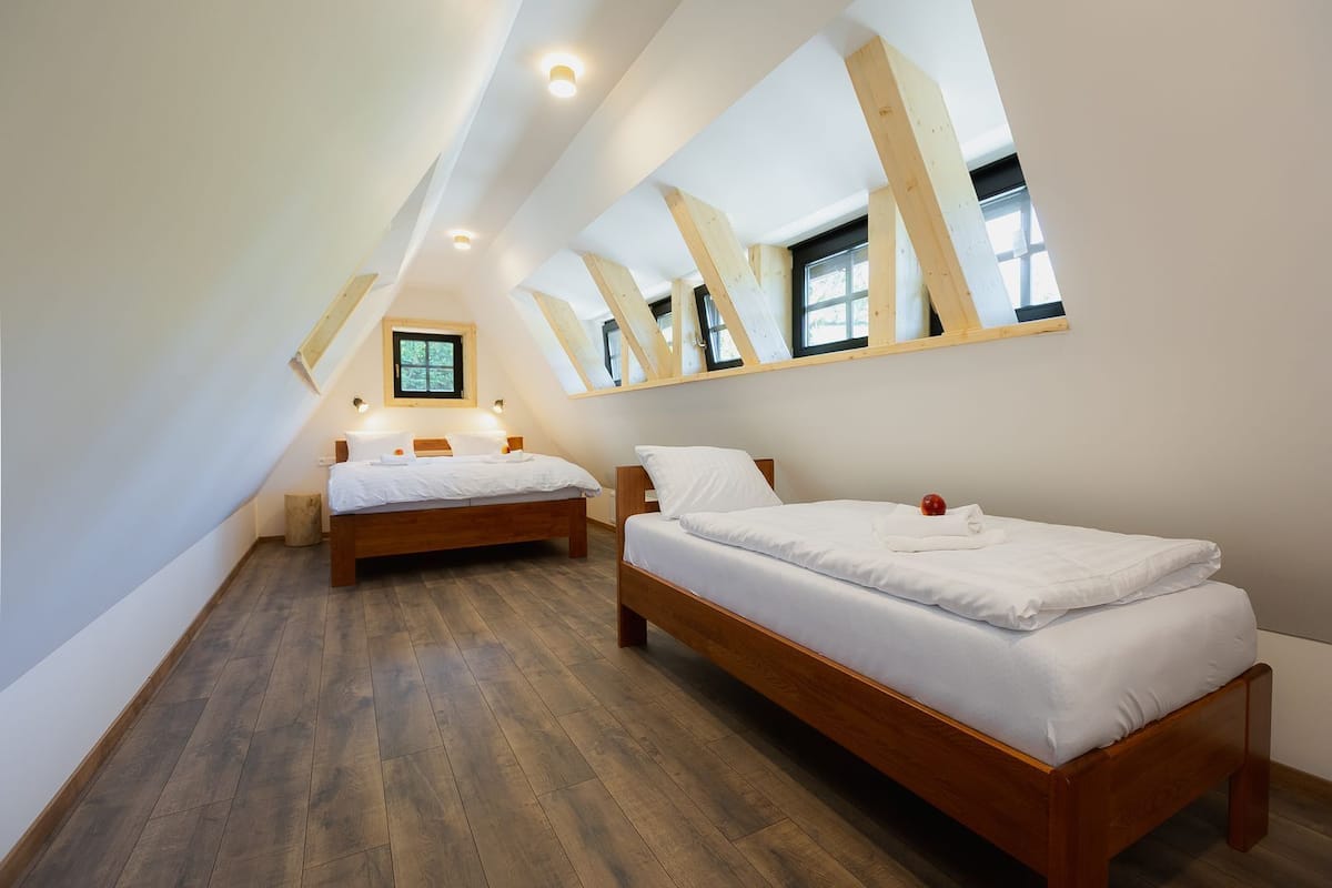 Ein Schlafzimmer mit zwei Betten, Holzbalken, einem Oberlicht und einem kleinen Fenster.