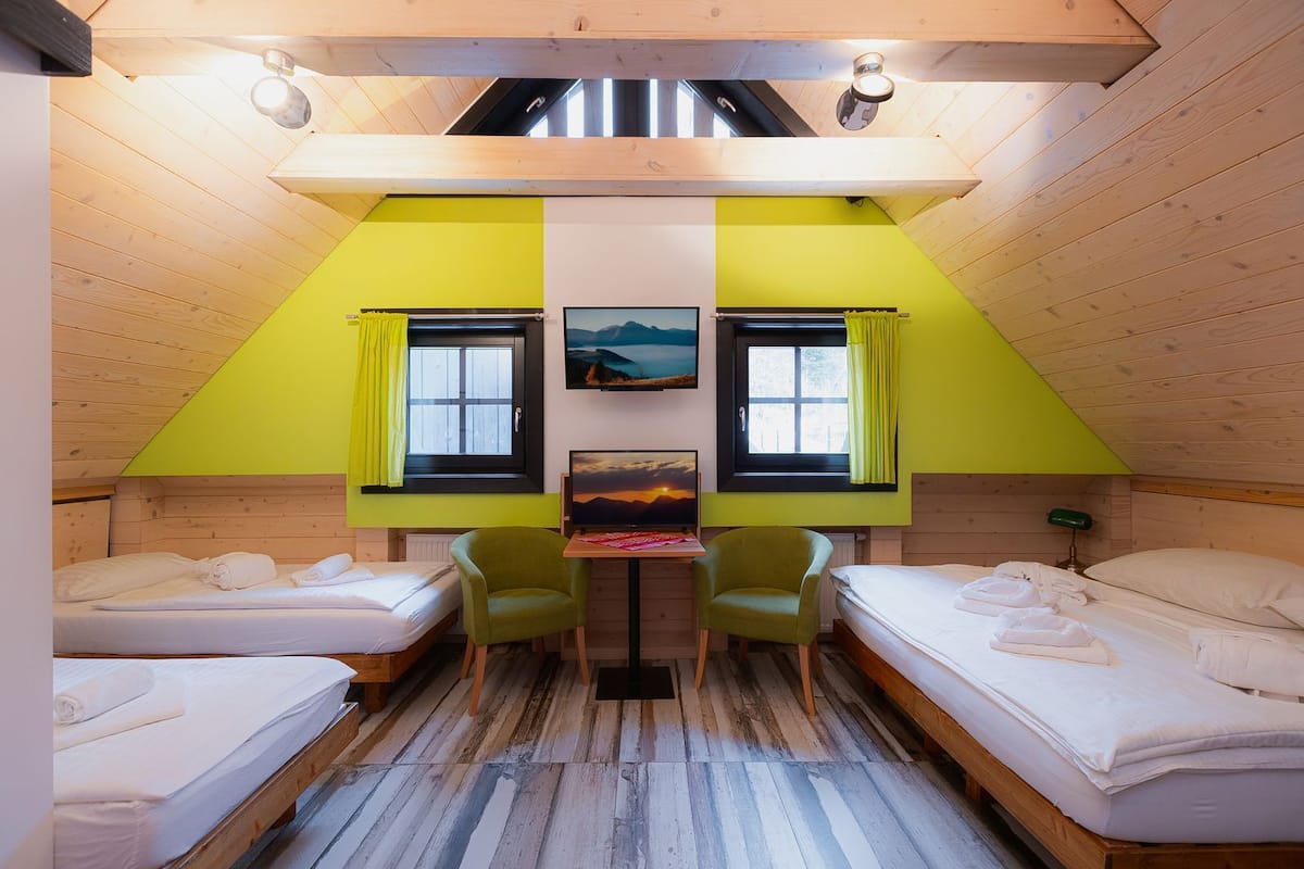 Ein gemütliches Zimmer mit zwei Betten, einem kleinen Tisch und zwei Stühlen.