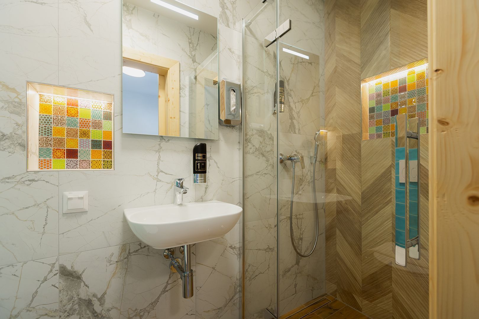 Une salle de bain dotée d’un lavabo en marbre, d’une douchette et d’une cabine de douche en verre.
