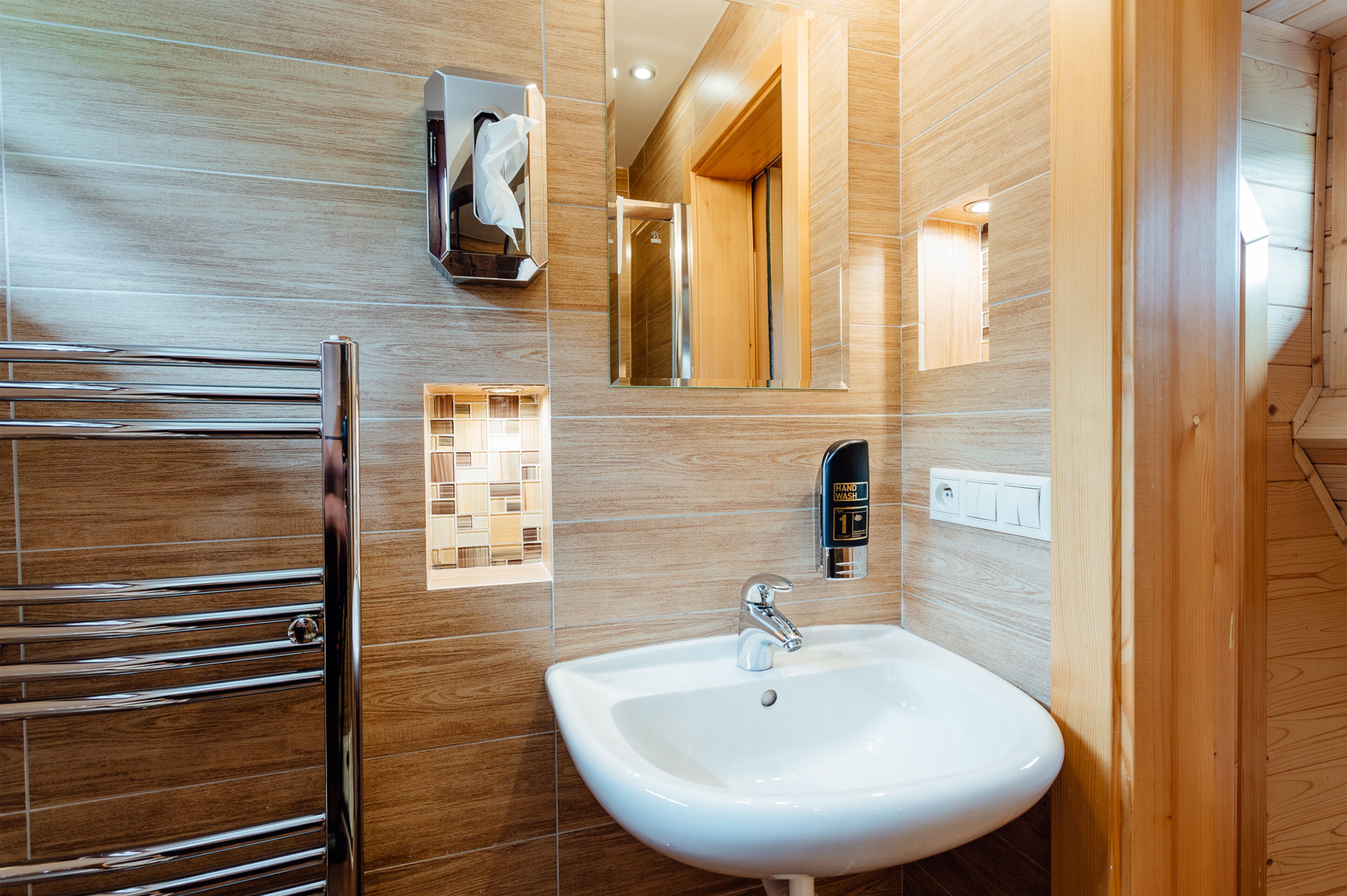 Un baño moderno con un toallero cromado, un lavabo blanco y un espejo.