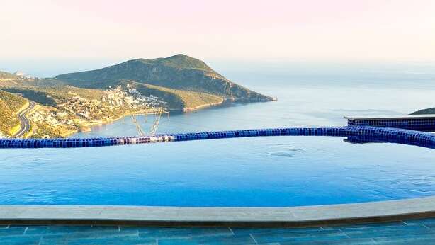Una gran piscina infinita con vistas a un pueblo costero y una montaña.