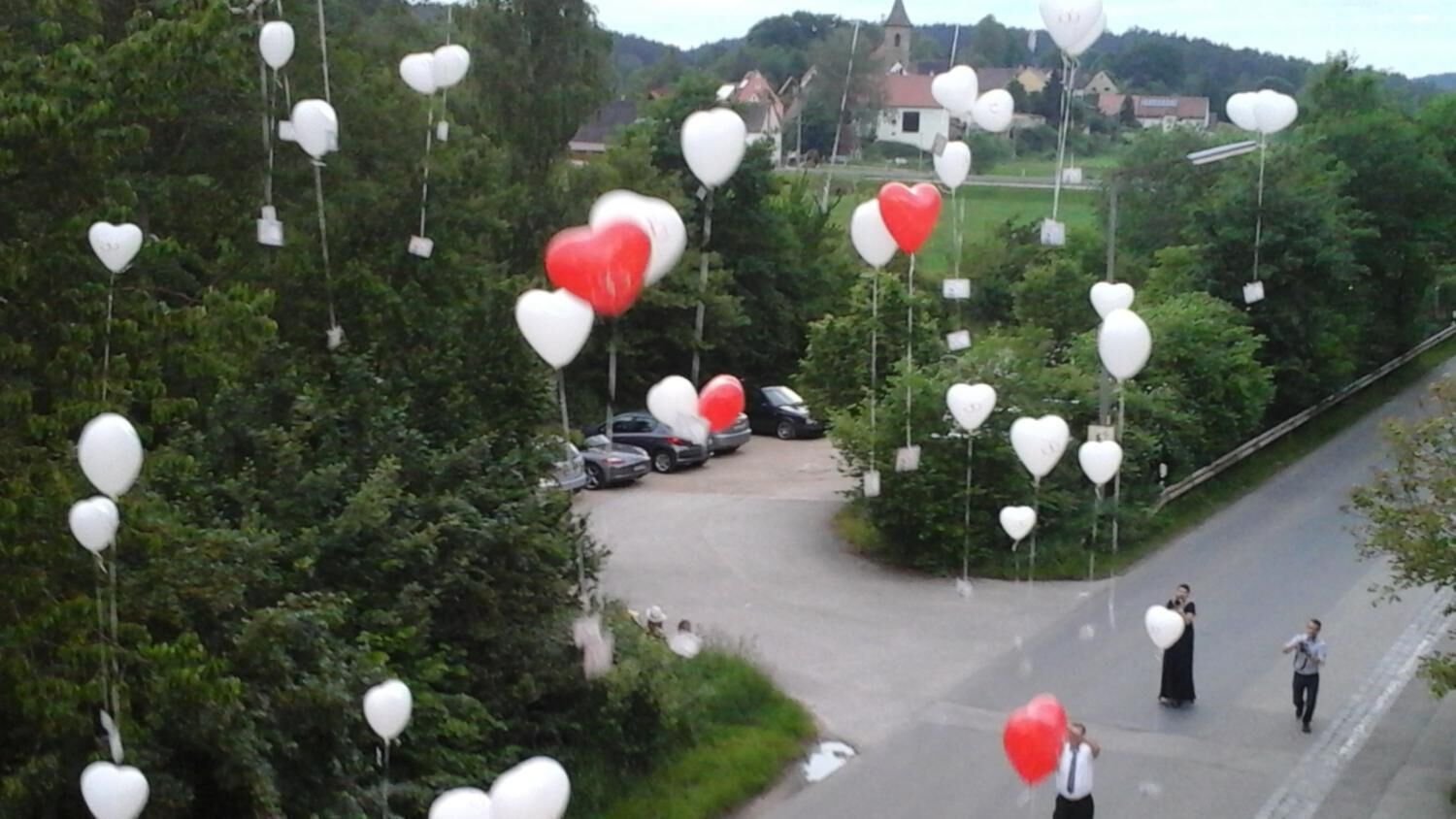Une route bordée de ballons en forme de cœur, avec une église en arrière-plan.