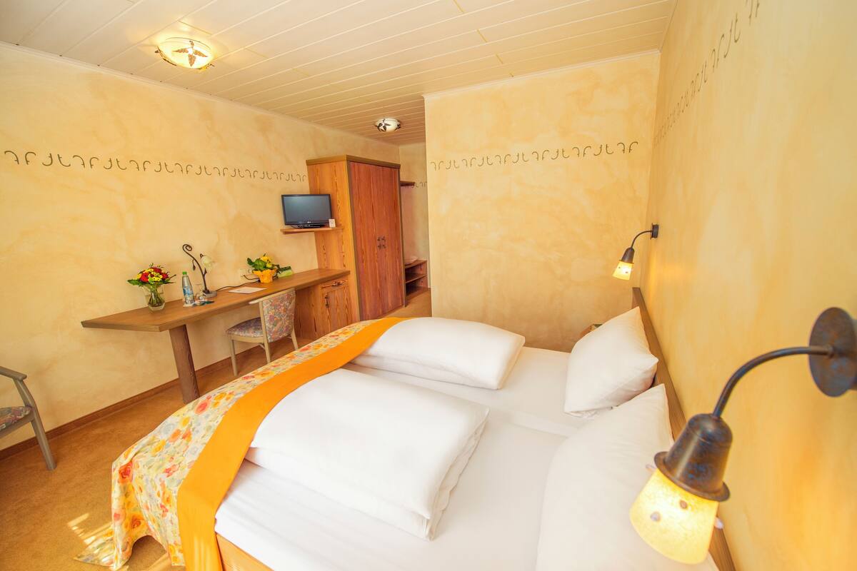 Une chambre d’hôtel avec un lit, un bureau doté d’une télévision et une lampe fixée au mur.