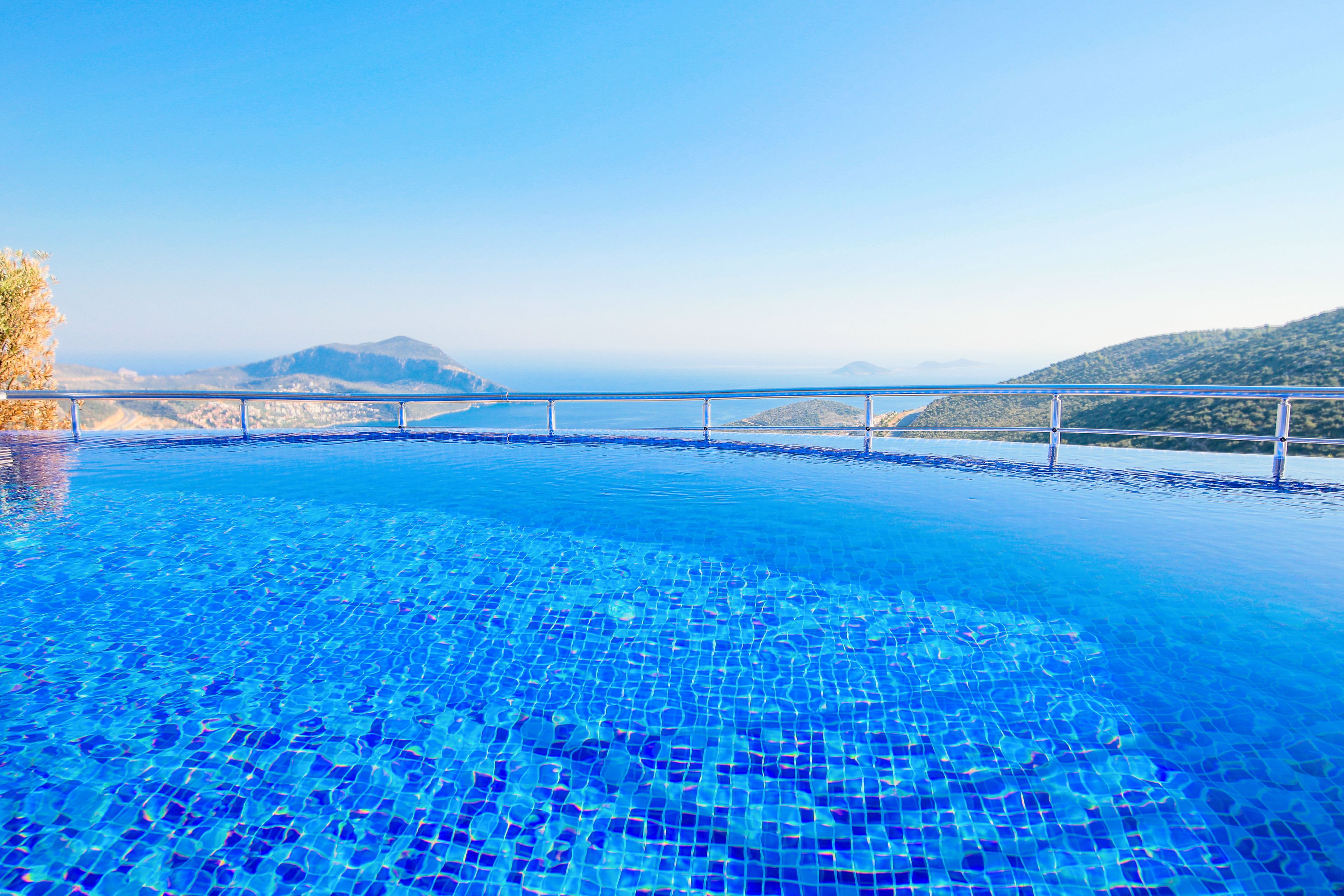 A clear blue infinity pool with a view of distant mountains and a clear sky.
