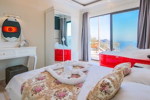 A hotel room with a bed, a desk, a mirror, and a large window with a view.