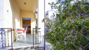 A balcony with a stone floor, white chairs, and a table with a red tablecloth. - Appartamento La Posta Pomonte (Marciana)