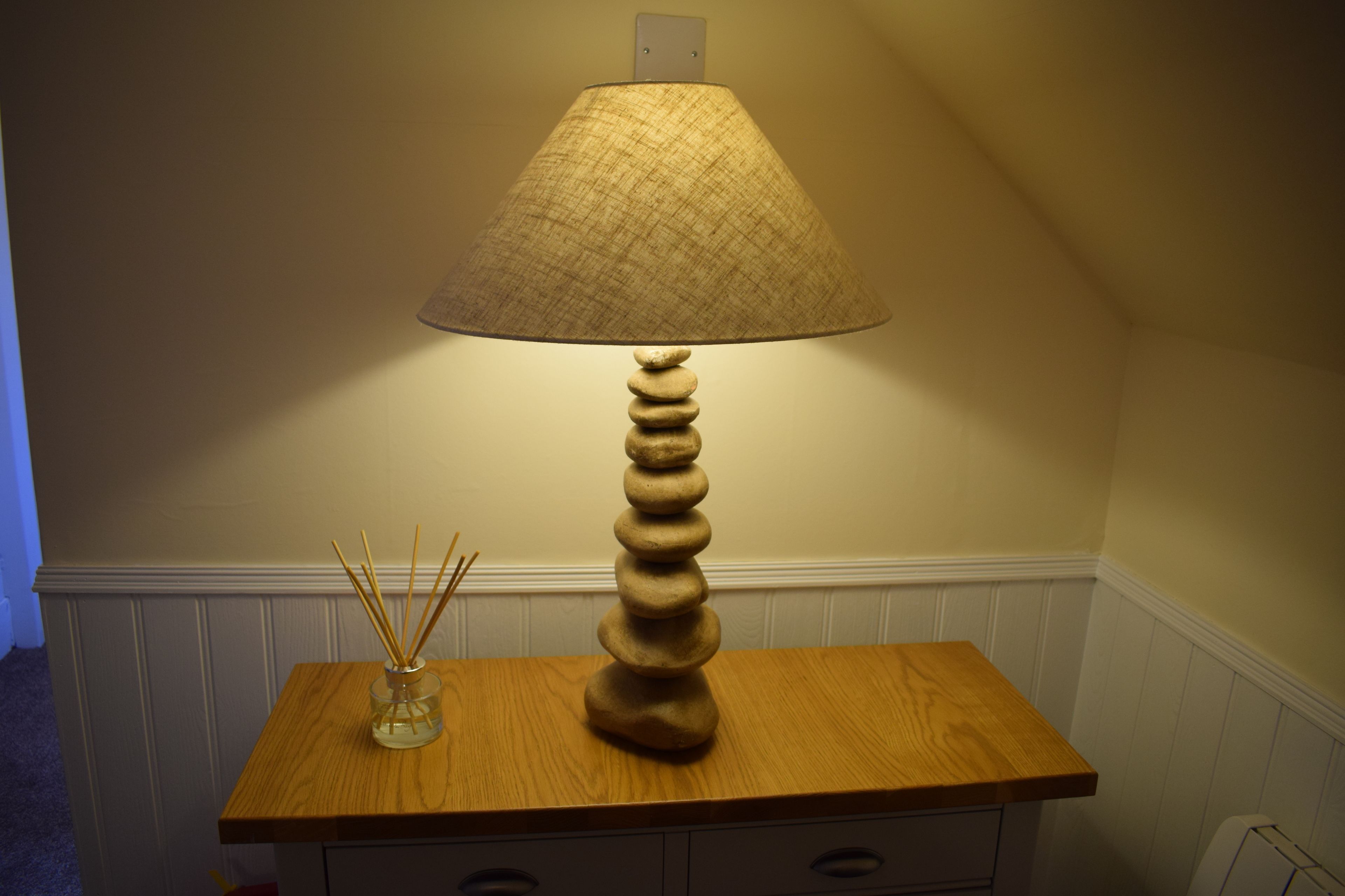 En lampa med en lampskärm som har en intressant yta, placerad på ett träbord.
