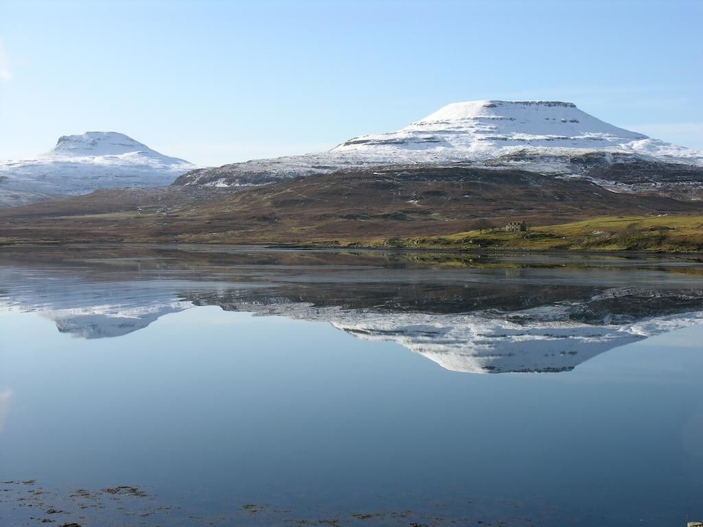 Un lago tranquilo que refleja una montaña nevada, bajo un cielo despejado.
