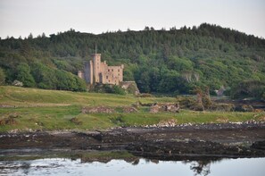 A castle on a hill with a body of water in the foreground. - The Tables Guest House (Dunvegan)
