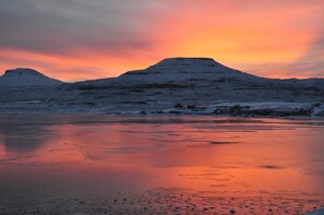 A frozen landscape with snow-covered hills and a reflective ice surface. - The Tables Guest House (Dunvegan)