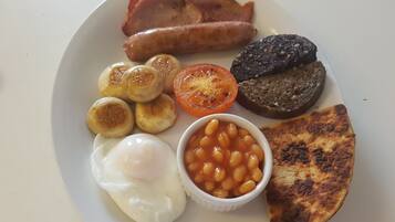 Prato de comida de café da manhã com bacon, linguiça, ovos, feijão cozido, tomate e torradas.