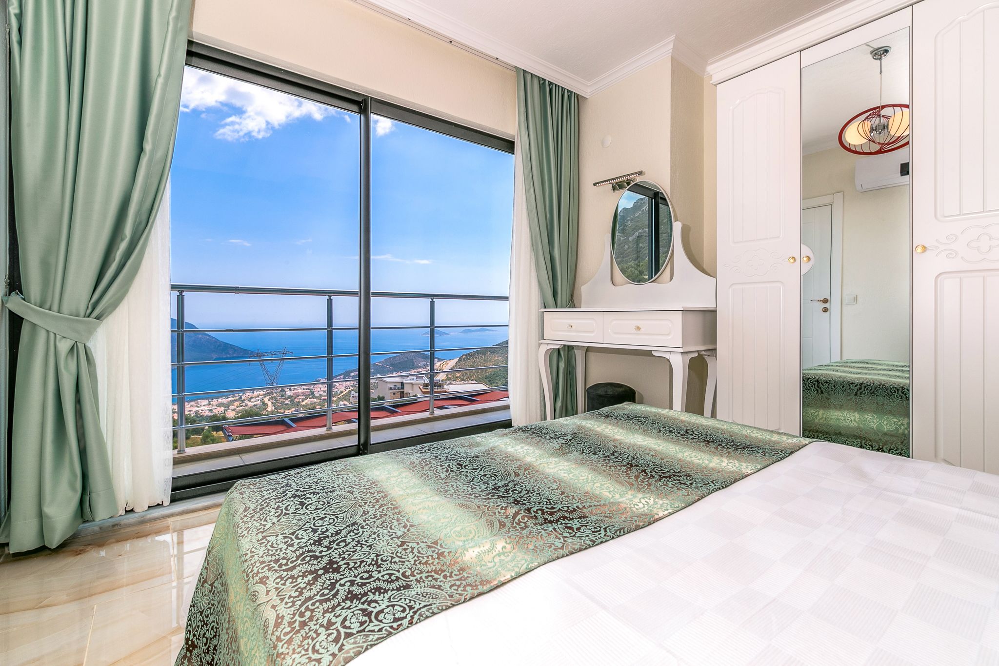 A bedroom with a large window, a bed, a dresser, and a mirror.