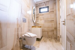 Un baño moderno con piso de mármol, inodoro, lavamanos con lavabo dorado y espejo.