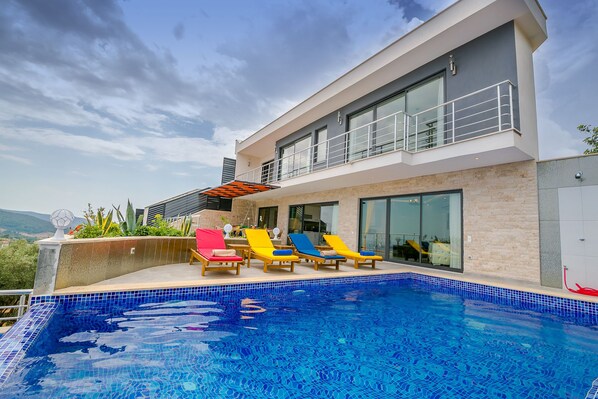 Una casa moderna con piscina, balcón y vistas a las montañas.