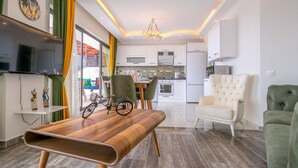 A modern living room with a wooden coffee table, a television, and a dining area with chairs. - Villa Nature - Hill Villas Kalkan (Kas)
