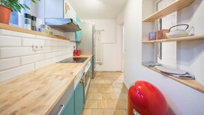 Cocina compacta con encimera de madera, una pelota de ejercicios roja y una ventana con estantes.