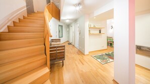 Una escalera conduce a un dormitorio con suelo de madera y una cama.