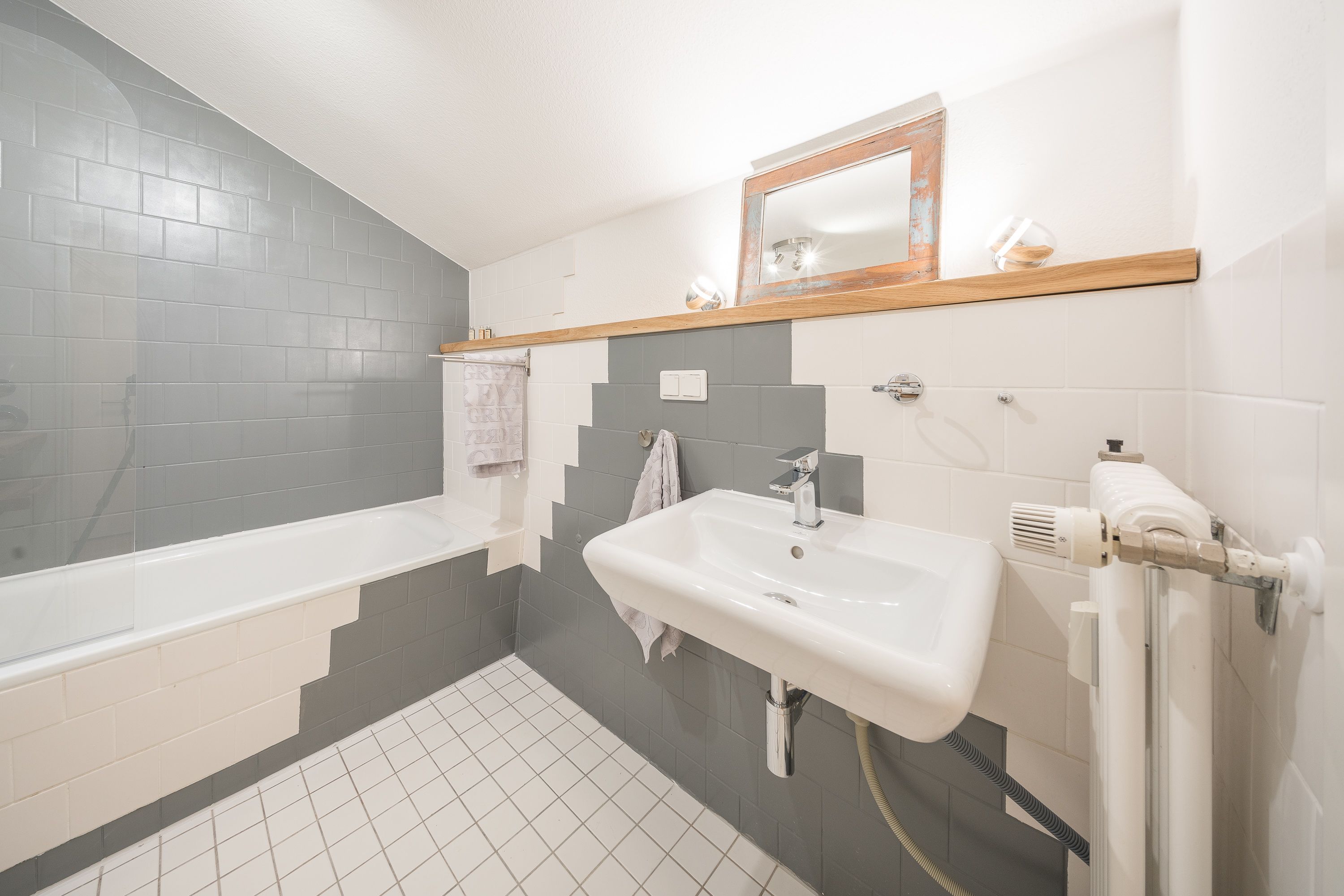 A bathroom with a bathtub, a sink, and a mirror.