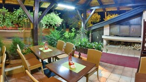 An indoor dining area with wooden tables and chairs, surrounded by potted plants and a fireplace. - B&B Mreznica House DP (Duga Resa)