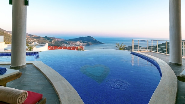 Une piscine à débordement offrant une vue sur la mer et les montagnes.