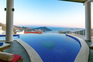 A infinity pool with a view of the sea and mountains.