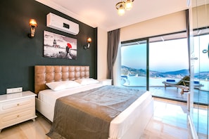 A modern bedroom with a large bed, a nightstand, a wall-mounted air conditioner, and a painting of a lighthouse.