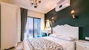 Une chambre avec un grand lit, une table de chevet, un bureau et une chaise. Il y a une fenêtre avec des rideaux et une vue sur l’extérieur.