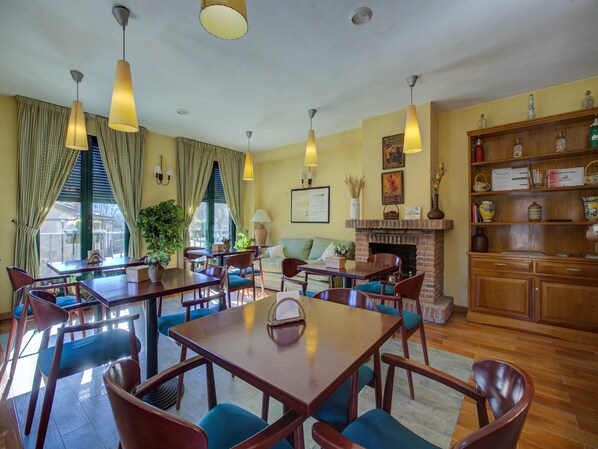 A hotel lobby with a dining area, seating arrangements, and a fireplace.