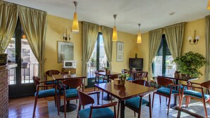 A dining area with wooden tables and chairs, a television, and a potted plant. - Hostal la Chata by Vivere Stays (La Granja de San Ildefonso)