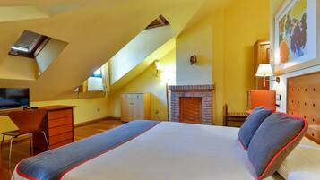 A bedroom with a bed, a desk, a chair, a TV, a fireplace, and a painting on the wall.