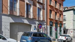 A multi-story building with balconies, parked cars, and a clear blue sky. - Hostal la Chata by Vivere Stays (La Granja de San Ildefonso)