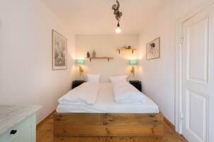 Un dormitorio ordenado con una cama de madera, dos mesitas de noche con lámparas y estanterías en la pared.