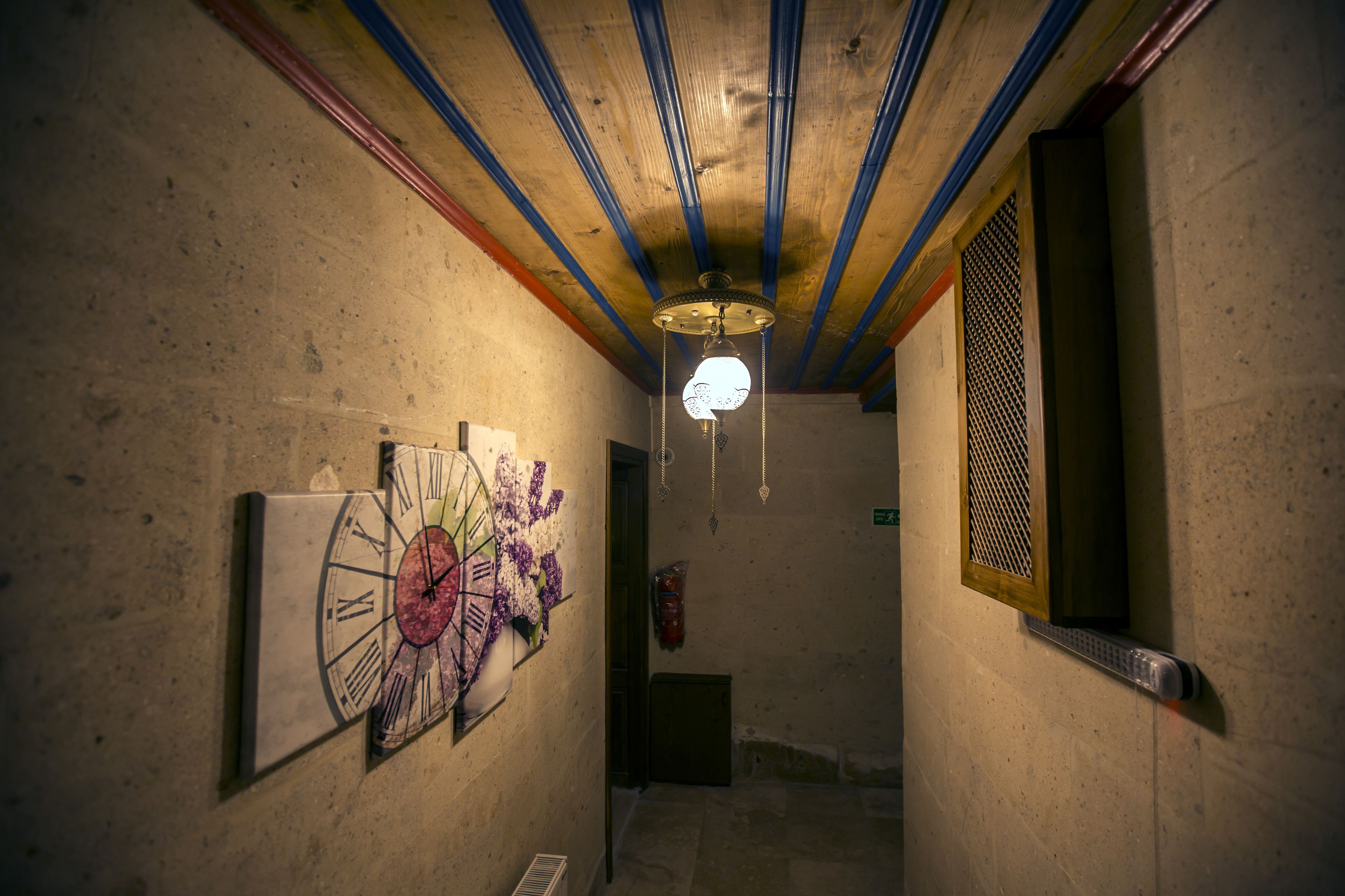 A hallway with a clock, a ceiling fan, and a window with a metal grill.