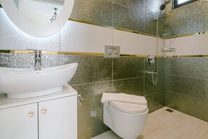 A bathroom with a white sink, a toilet, and a shower area.