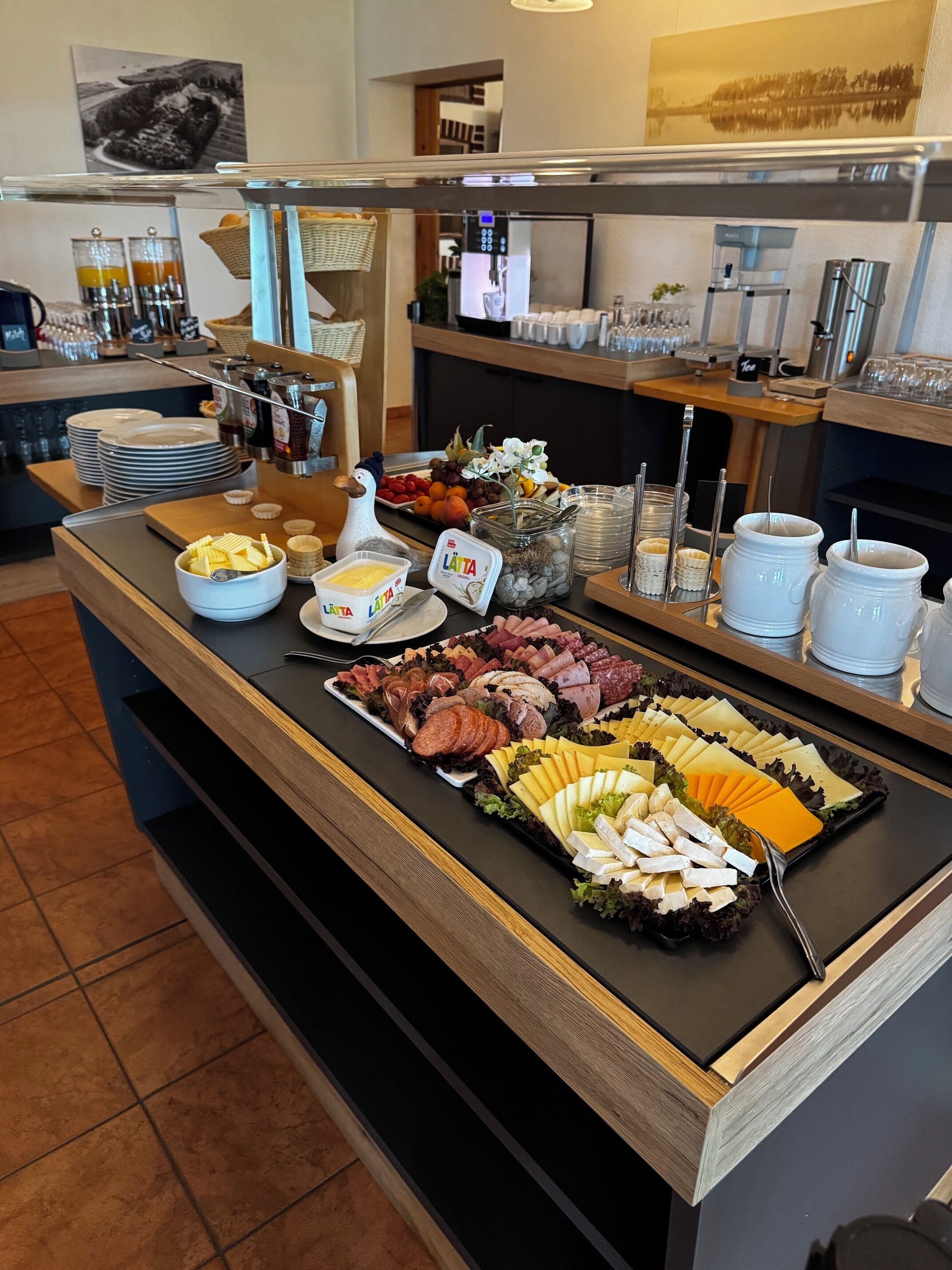 Een buffet met diverse gerechtjes, een koffieapparaat en een koelkast op de achtergrond.
