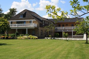 A two-story building with a balcony, a sign reading "YOUNG'S," and a well-maintained lawn. - Pension Treenehof (Koldenbüttel)