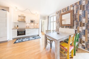 Una cocina moderna con armarios blancos, una mesa de comedor de madera y sillas coloridas.