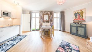 A modern kitchen with a microwave, a dining table with chairs, and a large window with curtains. - Design Apartments "Potsdam West" (Potsdam)