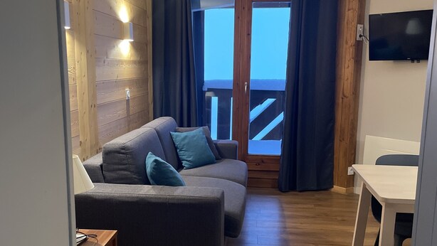 A cozy living room with a sofa, a TV, and a wooden floor. - Val Tho, 1 bedroom, on the slopes, parking - 2 other apartments available next door  (Val Thorens)