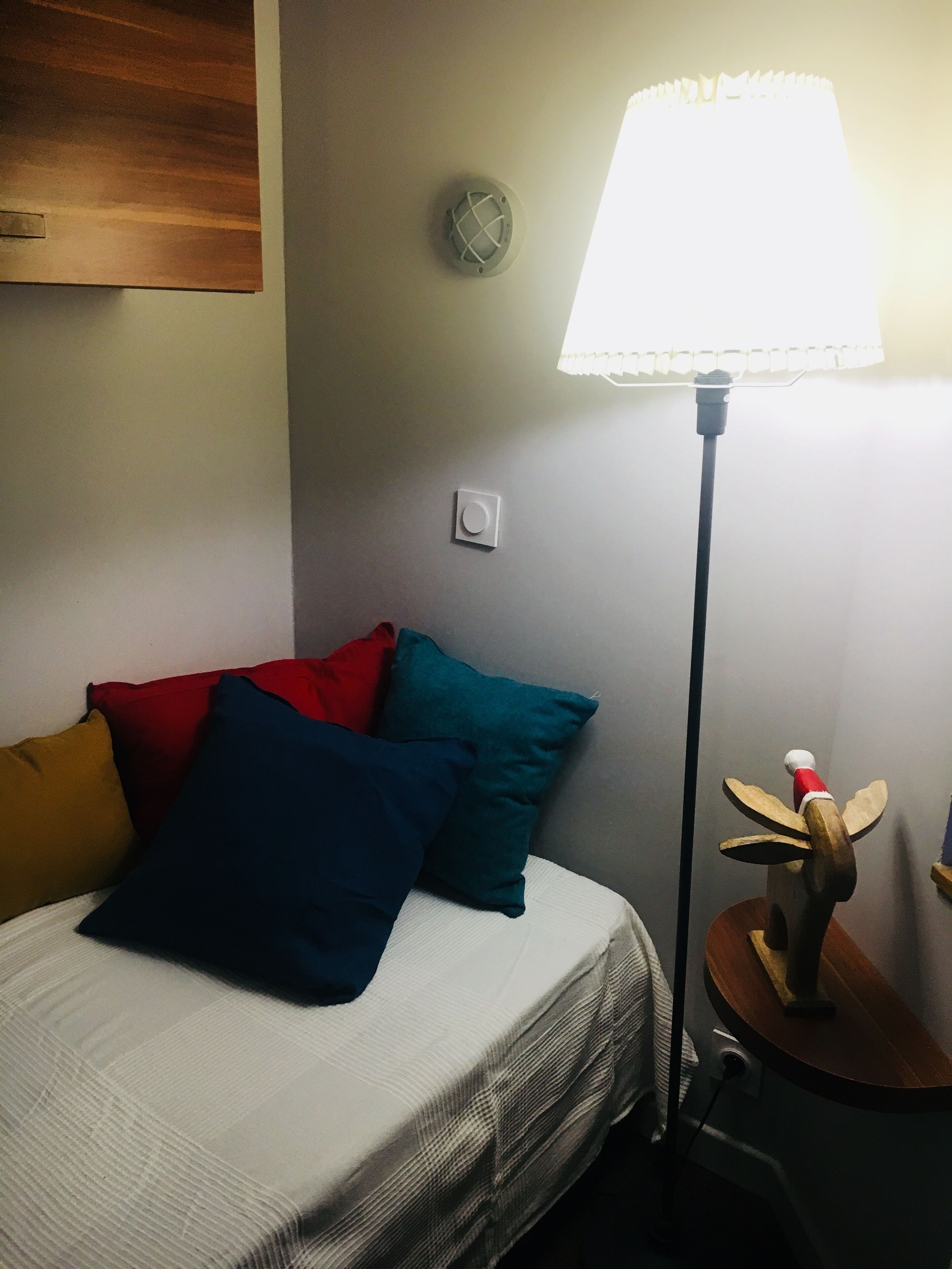 A hotel room with a bed, pillows, a lamp, and a wall clock.
