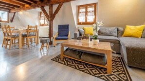 A cozy living room with a wooden dining table, chairs, a sofa, and a coffee table. - Charming Alsatian triplex house rated 3*, Ribeauvillé center (Ribeauvillé)