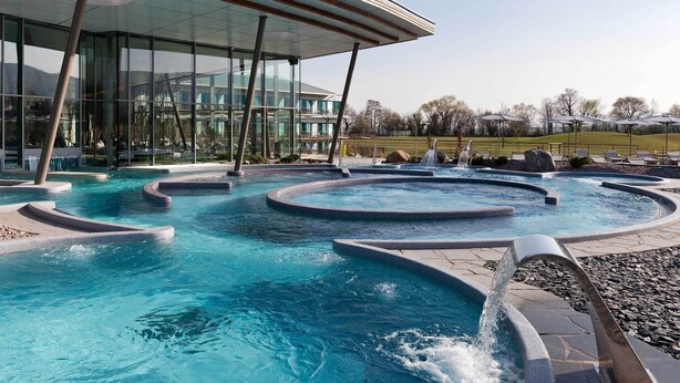 A modern outdoor pool area with multiple water features and a glass building in the background. - Charming Alsatian triplex house rated 3*, Ribeauvillé center (Ribeauvillé)