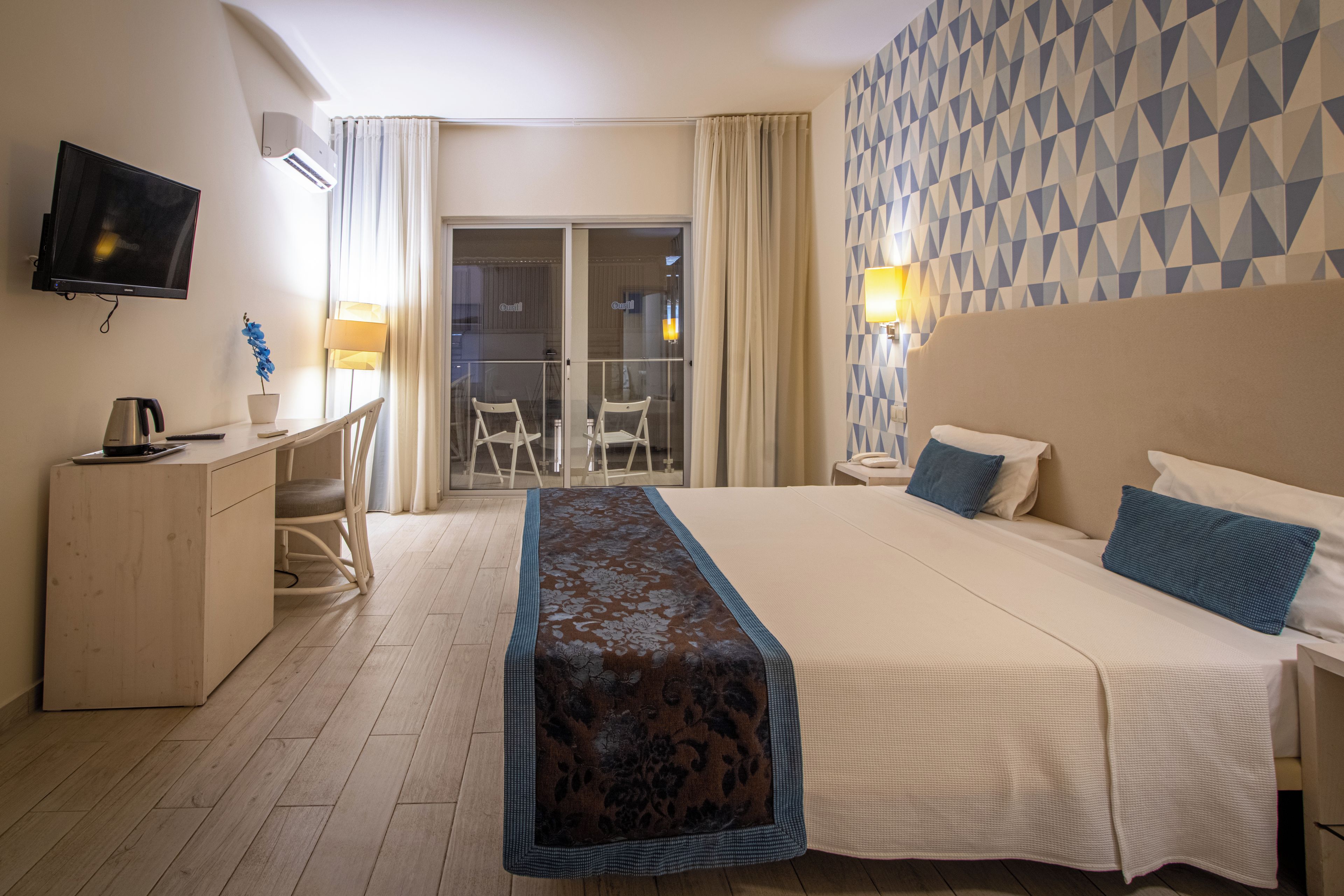 Camera d'albergo con un letto, una scrivania, una sedia, una TV e vista sull'esterno.
