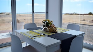 A dining table with a vase of yellow flowers, a black table runner, and a yellow placemat. - Ouril Agueda (Boa Vista)