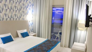A hotel room with a bed, a nightstand, a lamp, and a view of the outside through a window. - Ouril Agueda (Boa Vista)