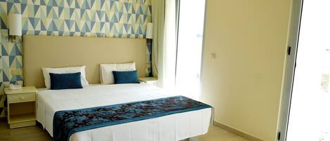 A hotel room with a large bed, a nightstand, a lamp, and a geometric-patterned wall.