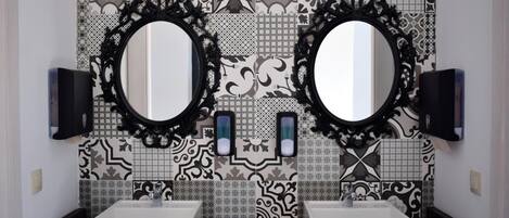 A bathroom with two sinks, black marble countertops, and ornate black-framed mirrors.